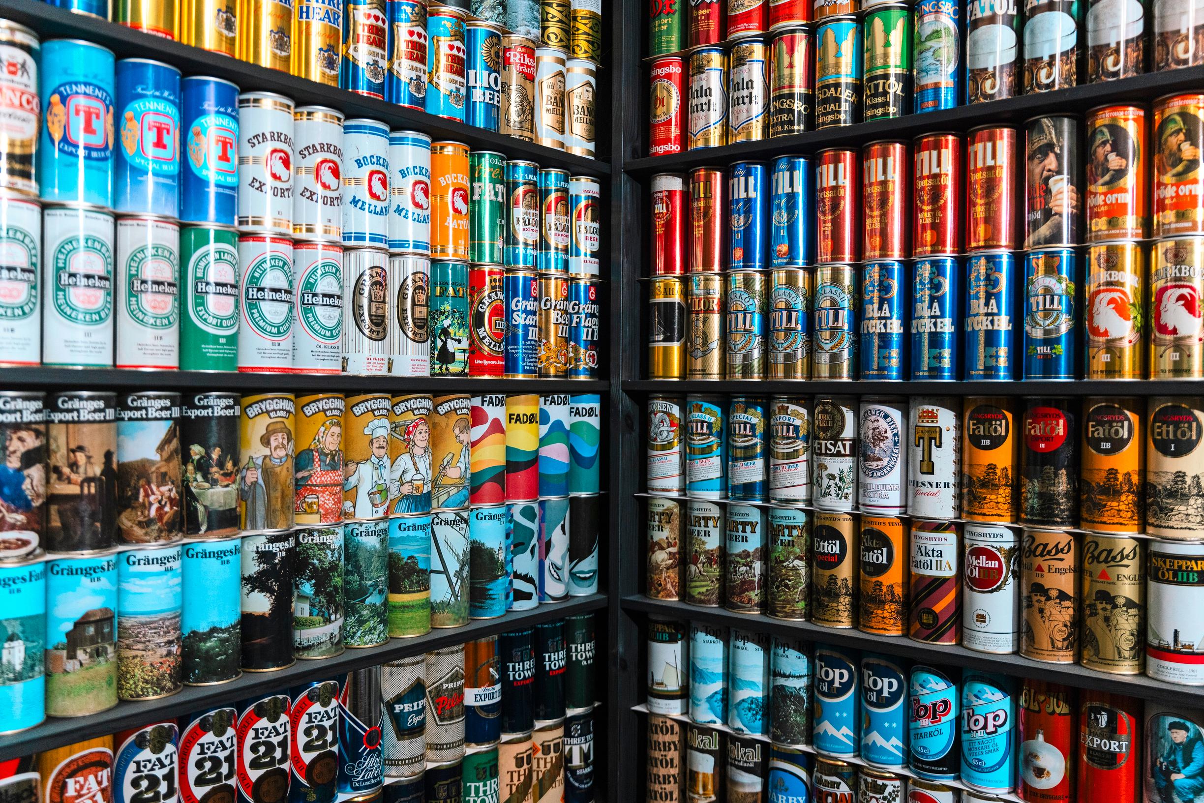 Hyllyriveittäin värikkäitä tölkkejä tasaisesti vierekkäin aseteltuna.