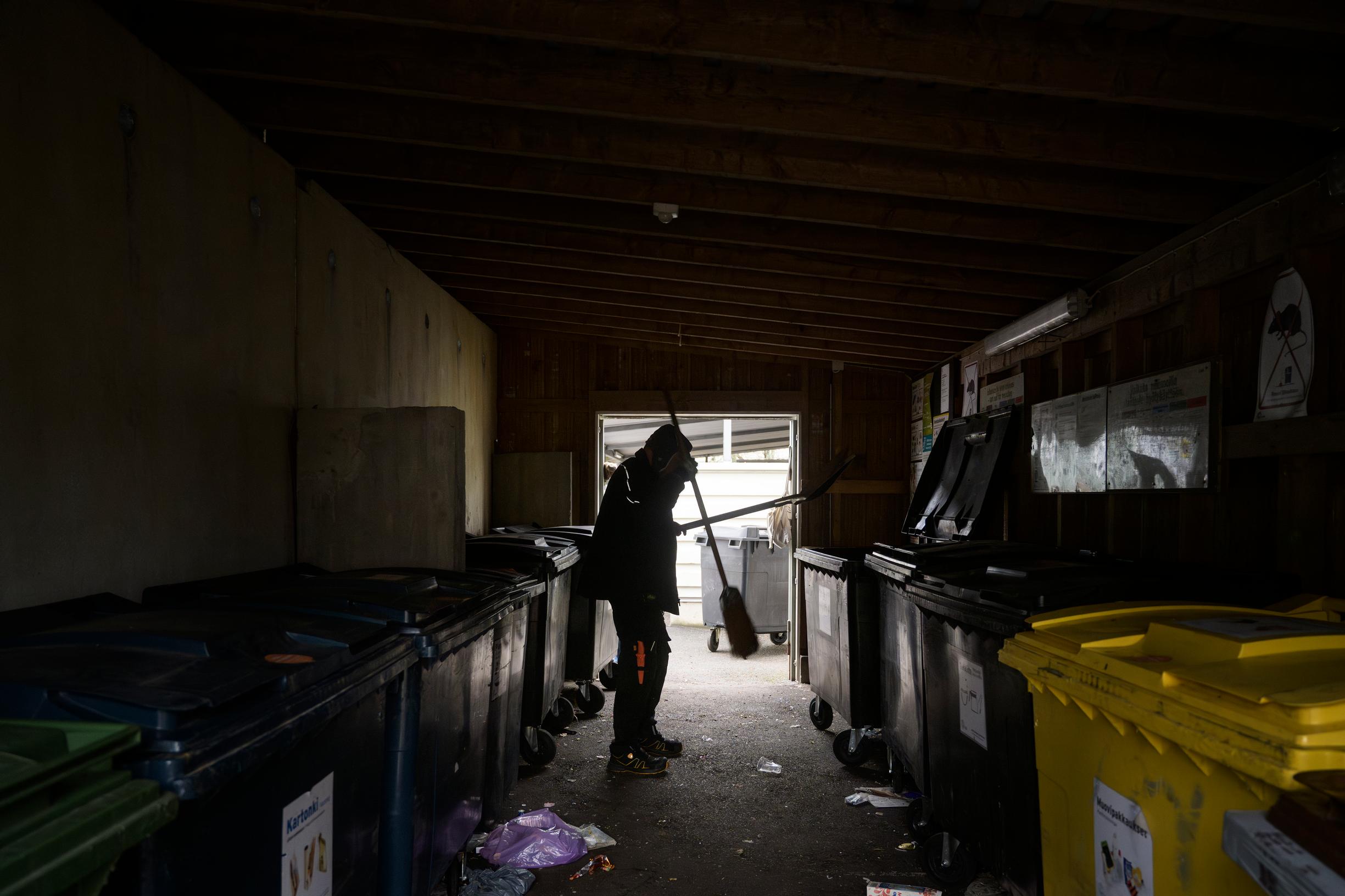 Huoltomies puhdistaa roskakatoksen lattiaa. Sotku on jokapäiväistä, eikä sitä aina ehdi muiden töiden vuoksi siivota.