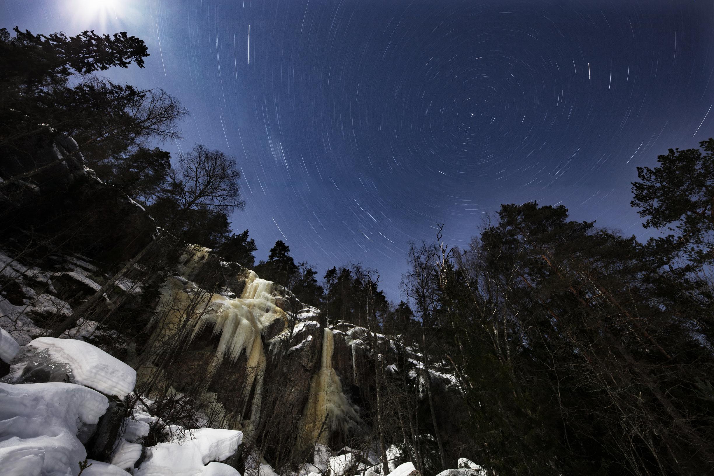Romvuoren jyrkänne kylpee kuunvalossa. Kamera on valottanut kuvaa 17 minuuttia, ja sinä aikana maapallon pyörimisliike on saanut tähdet piirtymään viiruiksi.