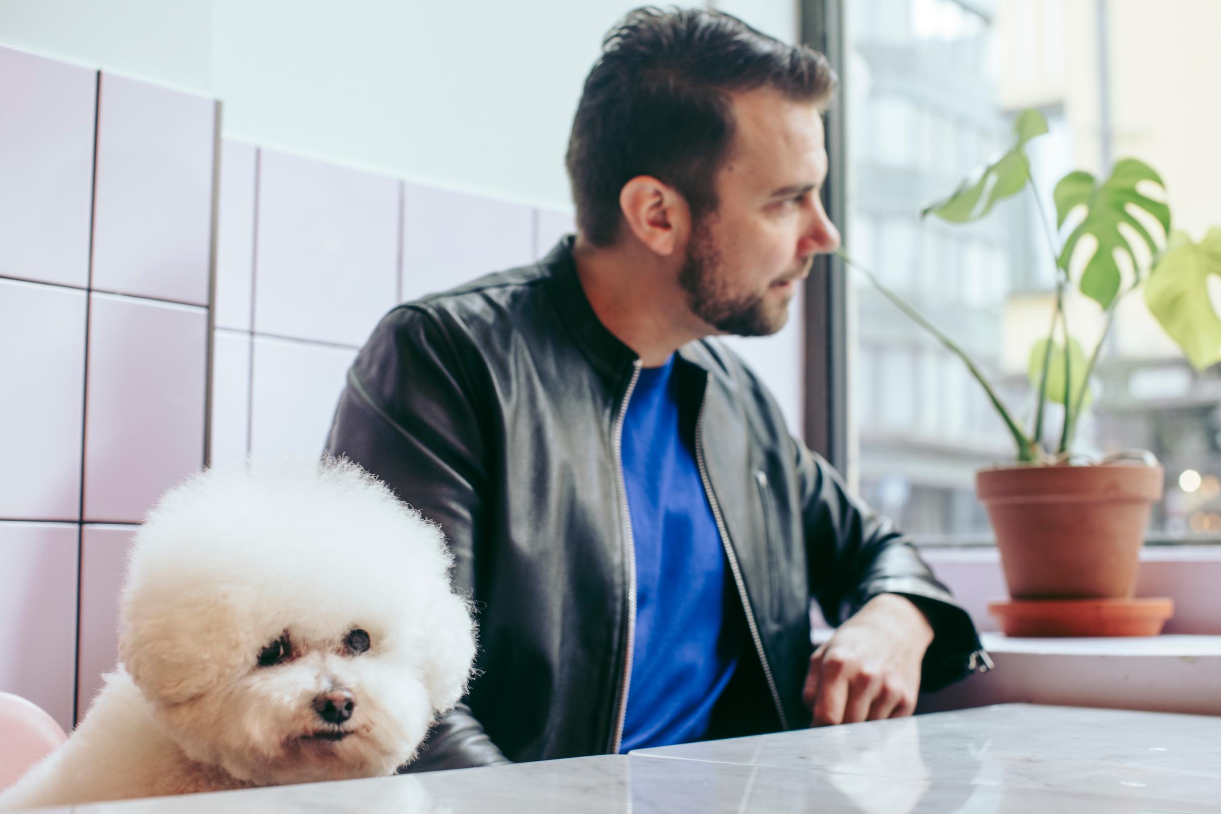 Antti Ketonen ja bichon frisé Elli vuonna pöydän ääressä.
