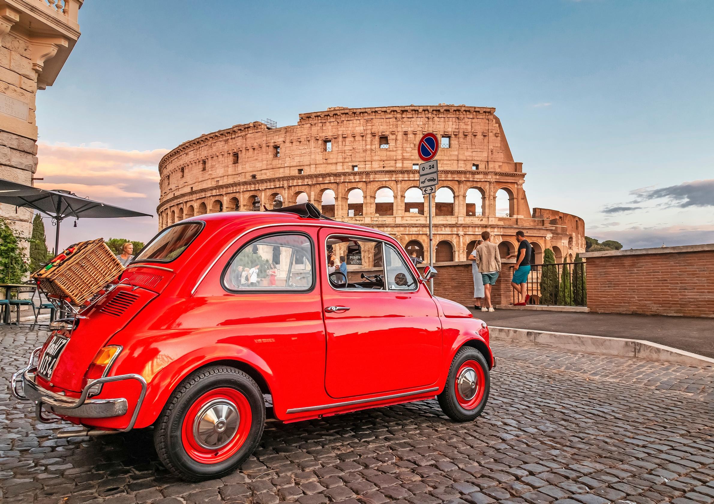 Fiat 500. Tämä on se alkuperäinen Fiat 500, jota nykyinen sähköauto yrittää niin kovasti jäljitellä. Taustalla Rooman Colosseum. 1950-luvulta peräisin olleessa originaali-Fiatissa käytettiin takamoottoria.