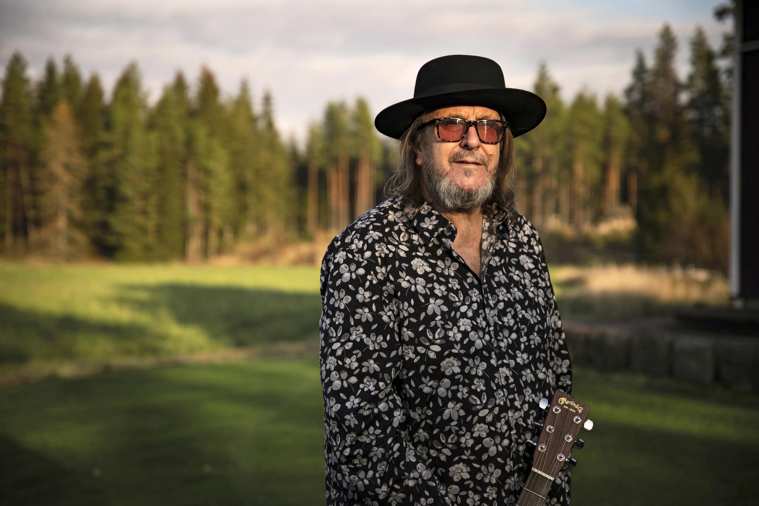 Heikki Hector Harma ulkona nurmikolla kitaran kanssa.