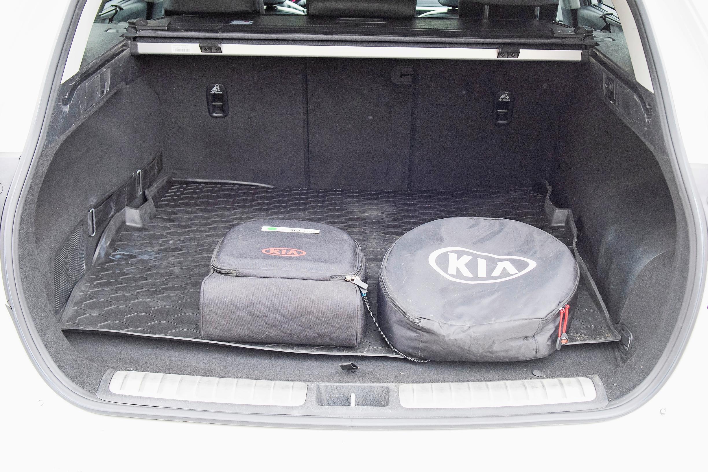 Kia Optiman latauskaapelit saa piiloon näihin säilytyslaatikoihin. Tavaratilan kumimatosta iso plussa.
