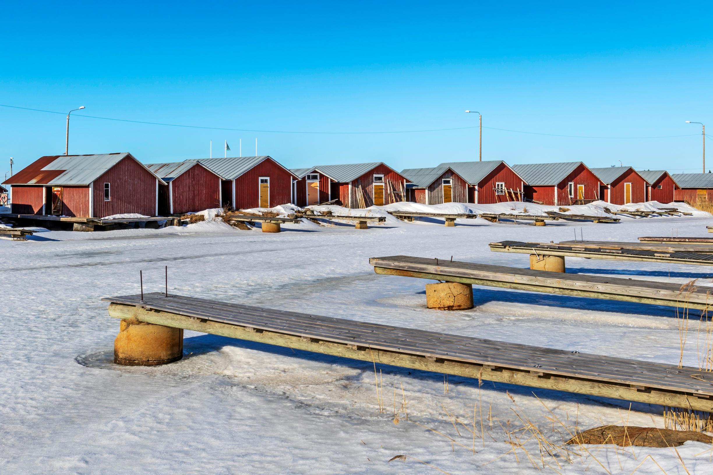 Merenkurkun De Geer -moreenille rakennettujen punaisten ranta-aittojen rivistö rajaa Svedjehamnin satamalahtea.
