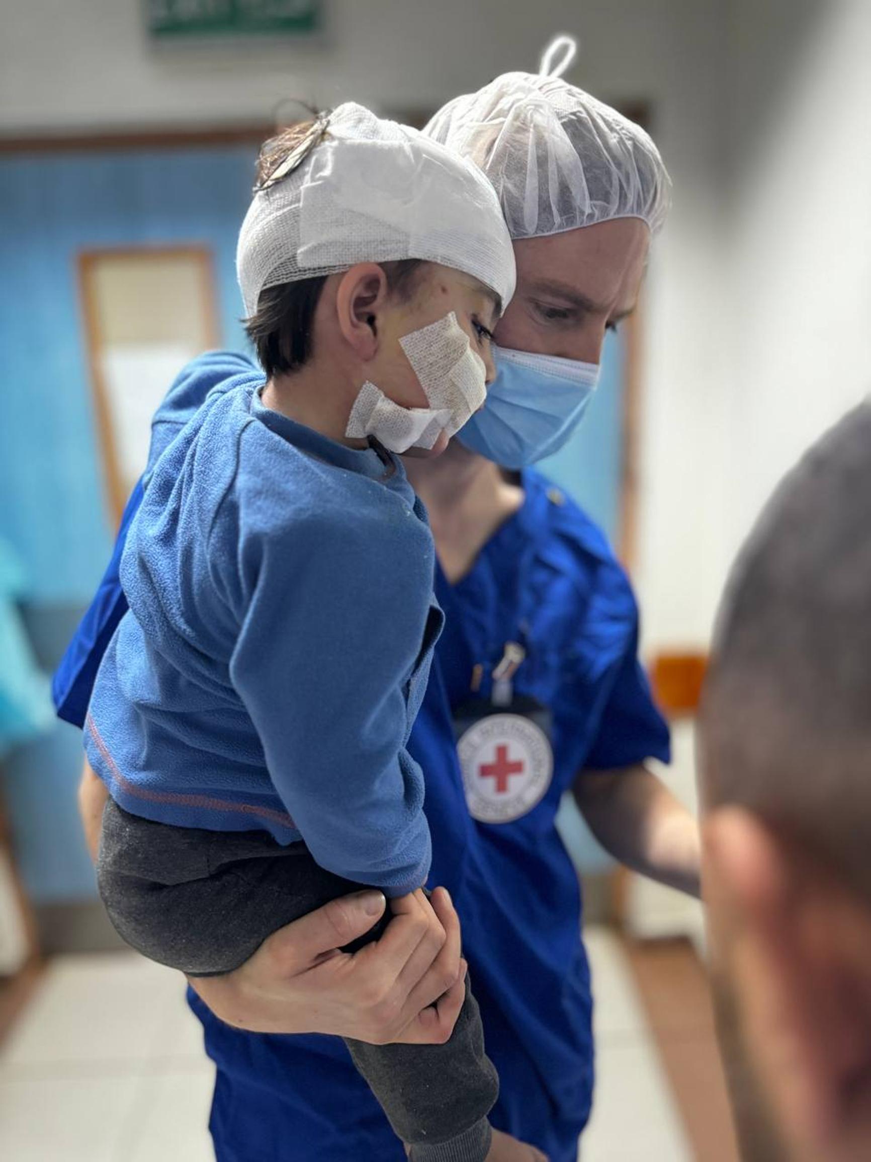 Lapsipotilas European Gaza Hospitalissa Punaisen Ristin avustustyöntekijän sylissä.